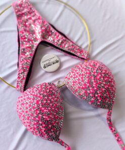Bikini de competencia en tonos rosas neos con destellos plateados, conector corazón reglamentario IFBB disponible. BikinisFitness